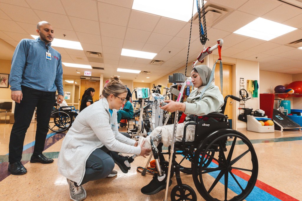 A physical therapist adjusts Layan’s test prosthetics in preparation for her to practice walking.